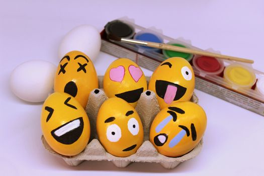Emoticons Easter Eggs in egg-cup , paints and brush with white background