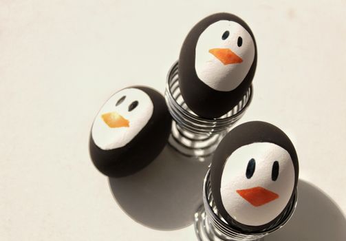 Penguin Easter Eggs made by hand on metal egg cup white background