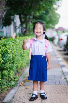 happy little girl in Thai school uniform with backpack standing in the park , ready back to school