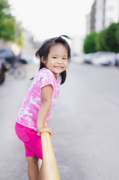 Little girl climbing yellow fence in the park