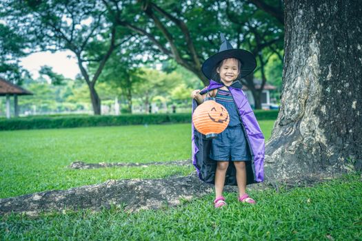 Little girl in a witch costume holding a lamp in halloween