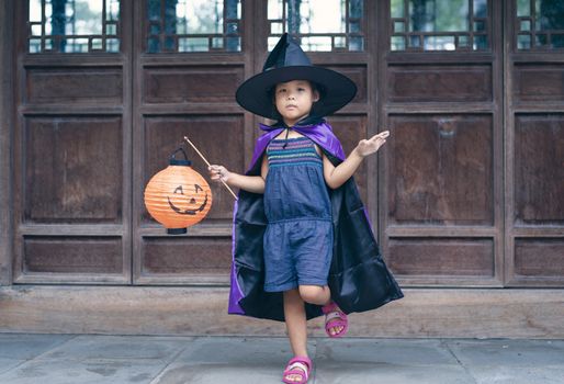 Little girl in a witch costume holding a lamp in halloween