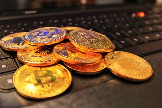 Golden bitcoins on black computer keyboard