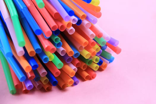 Colorful plastic drinking straws close up pink background