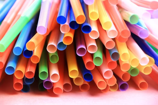 Colorful plastic drinking straws close up pink background