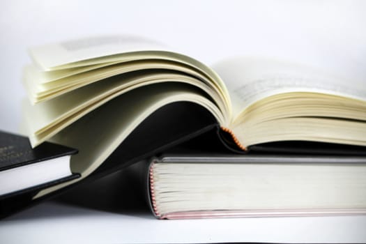 Black and white books stacked on white background one of them opened