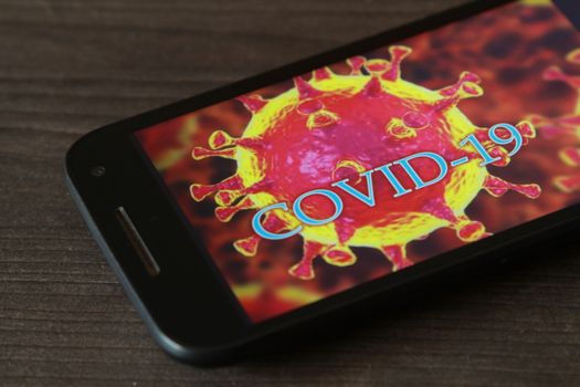 Madrid, Spain- April 23, 2020: Mobile phone on gray table with picture of covid-19 word on the screen