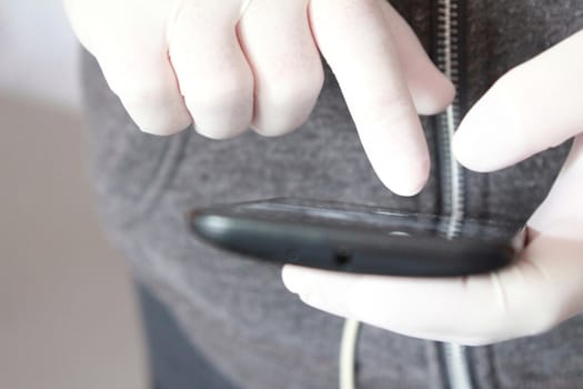 Hands in white latex surgical gloves holding a mobile phone