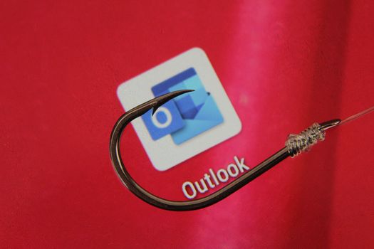 Madrid, Spain- May 10, 2010: Conceptual picture emulating phishing scam with a hook on Outlook icon on red screen