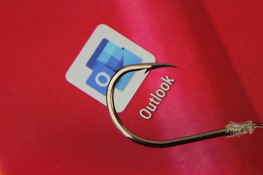 Madrid, Spain- May 10, 2010: Conceptual picture emulating phishing scam with a hook on Outlook icon on red screen