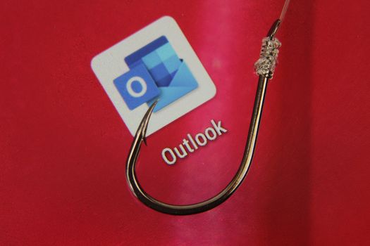 Madrid, Spain- May 10, 2010: Conceptual picture emulating phishing scam with a hook on Outlook icon on red screen