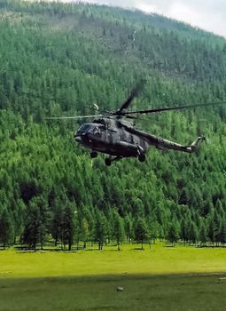 Helicopter MI-8 lands on edge in the woods in the mountains.