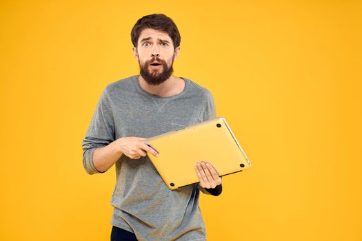 man with laptop wireless technology internet lifestyle work yellow isolated background. High quality photo