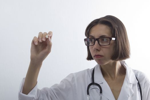 Female medical student with chalk in hand on white background