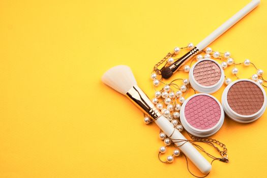 Eyeshadows and makeup brushes on a yellow background top view professional cosmetics. High quality photo