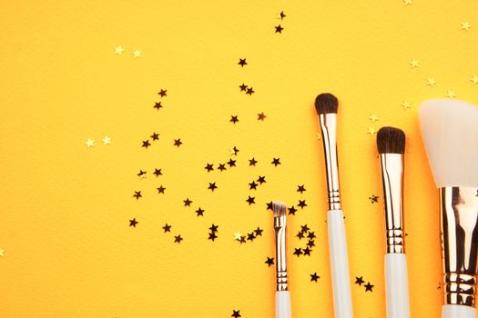 Makeup brushes in different sizes on a yellow background and glitter cropped look. High quality photo