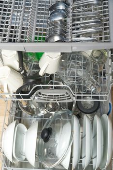 Dirty dish in open integrated dishwasher. full loaded dishwasher ready for washing. Open dishwasher with dirty dishes inside before washing.