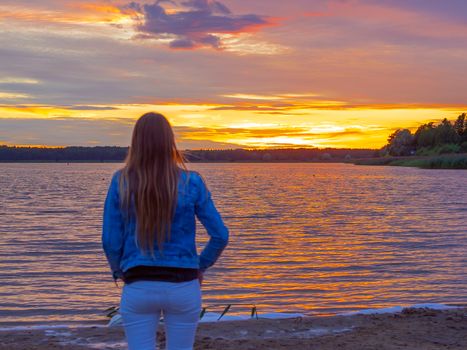 Portrait of young beautiful girl Watching sunset on the beach. Backview. Copy space. Image for wallpaper, background. Dramatic sky