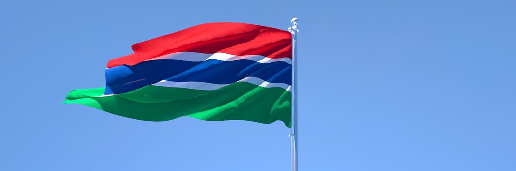 3D rendering of the national flag of Gambia waving in the wind against a blue sky.