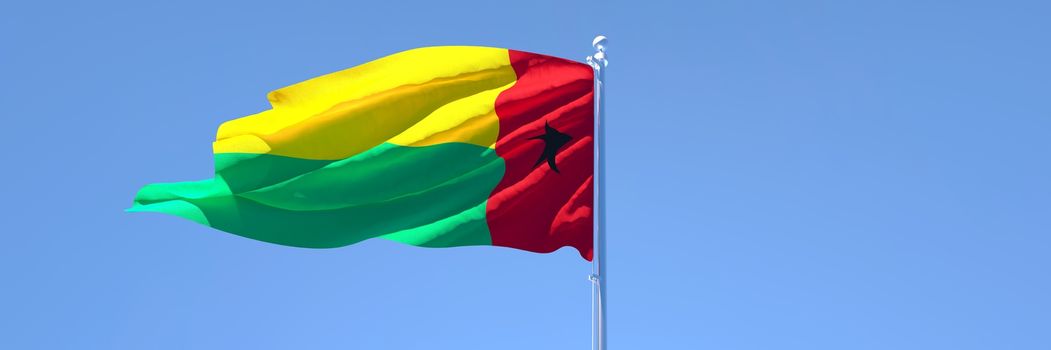 3D rendering of the national flag of Guinea Bissau waving in the wind against a blue sky