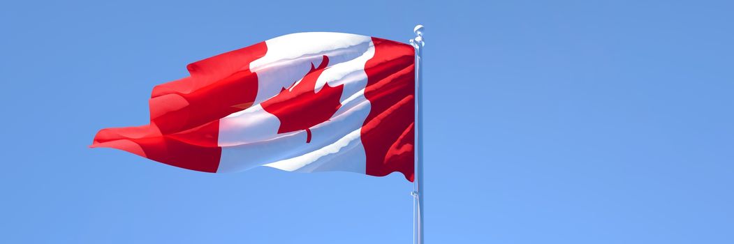 3D rendering of the national flag of Canada waving in the wind against a blue sky