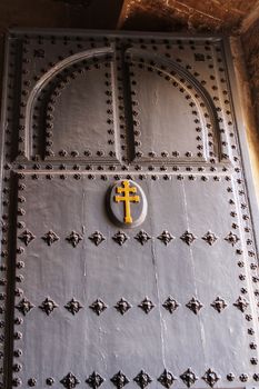 Old wooden gray door with wrought iron details in Caravaca de La Cruz, Spain