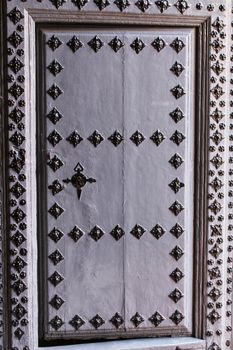 Old wooden gray door with wrought iron details in Caravaca de La Cruz, Spain