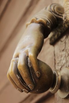 Golden doorknocker with hand shape on old brown wooden door in Alcaraz, Albacete, Spain