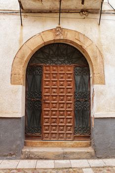 Old stone facade made of carved stone and vintage wooden door in a majestic house in Alcaraz, Albacete province, Spain.