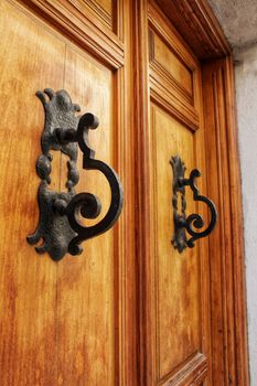 Forged metal vintage door knocker on brown wooden door in Alcaraz, Spain