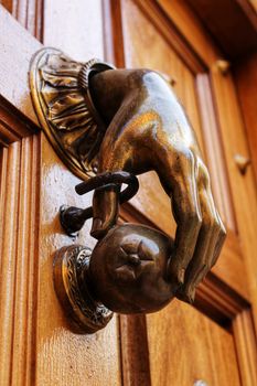 Golden doorknocker with hand shape on old brown wooden door in Alcaraz, Albacete, Spain