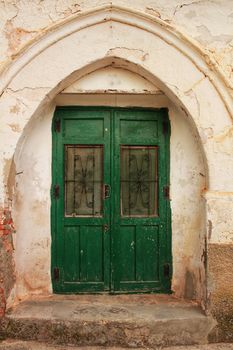 Old abandoned house facade with green wooden door with forged metal details in Oporto, Portugal