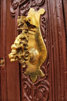 Beautiful golden door knocker with dog shape on old wooden door