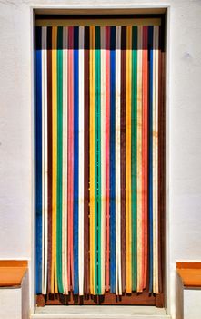Colorful and striped curtain on door of village house in Almeria, Spain