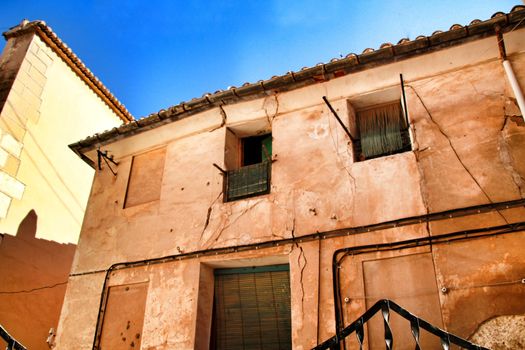 Old facade of old abandoned house with green blinds in Spain