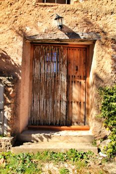 Old wooden door with wrought iron details on a stone facade in Riopar, Albacete, Spain.