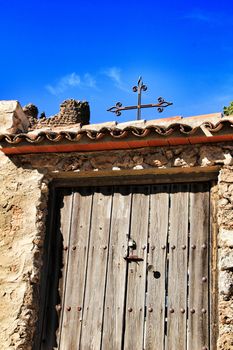 Old cemetery wooden door with wrought iron details on a stone facade in Riopar, Albacete, Spain.