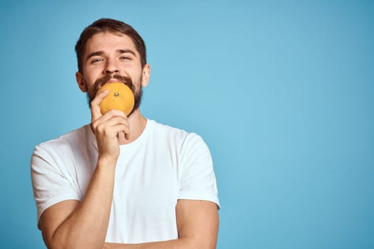 man with orange on blue background and cropped view Copy Space gesturing with hands. High quality photo