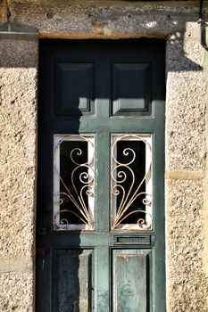 Old abandoned house facade with green wooden door with forged metal details in Oporto, Portugal