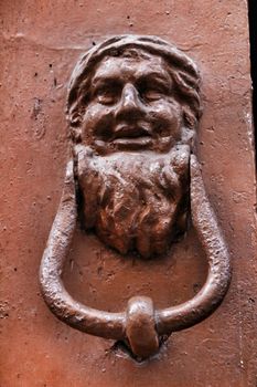 Vintage door knocker face shape on brown wooden door