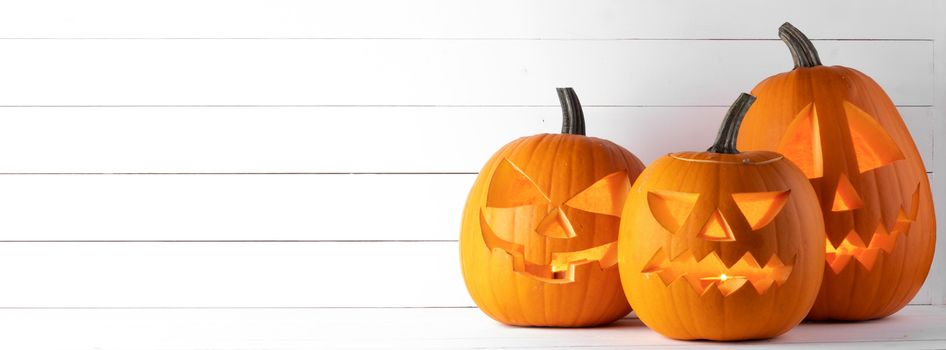 Halloween pumpkin head jack o lantern and candles inside on wooden background