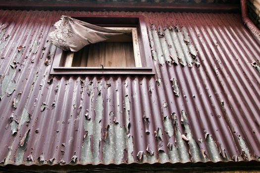 Old metal house facade with rusty window with curtain in Porto, Portugal