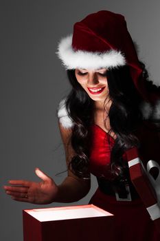 Beautiful santa girl opening glowing magic gift and smiling