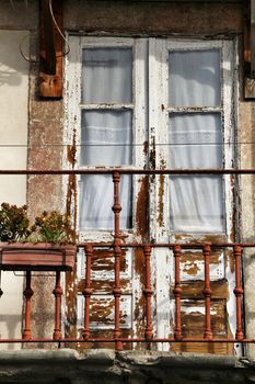 Old wooden window painted in white with crochet curtain in Porto, Portugal.