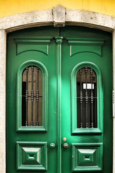 Green wooden door with forged metal details in Lisbon, Portugal.