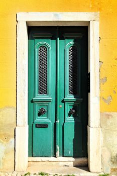 Old and colorful wooden door with iron details and yellow wall in Lisbon, Portugal