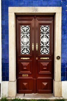 Old and colorful wooden door with iron details and blue tiled facade in Lisbon, Portugal