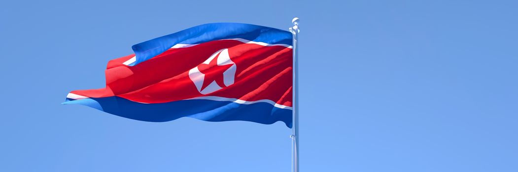 3D rendering of the national flag of North Korea waving in the wind against a blue sky