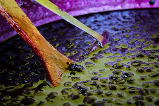 A wooden spoon and a metal ladle in a pot of chokeberry jam. Aronia jam in a pot. Zavidovici, Bosnia and Herzegovina.