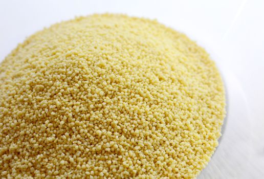 Closeup of raw uncooked cous cous heap in the bowl.